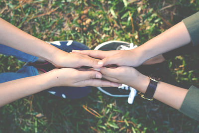 Low section of couple holding hands while sitting on field