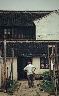 Rear view of man standing against built structure