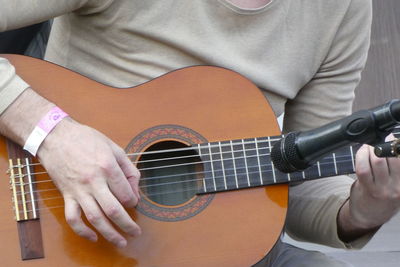 Midsection of man playing guitar