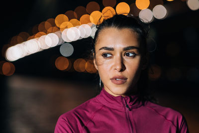 Portrait of young woman looking away at night