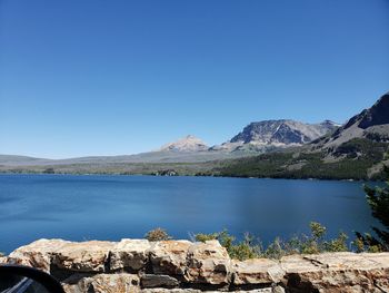 Scenic view of lake by mountains against clear blue sky