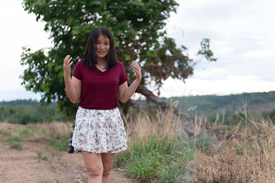 Portrait of smiling young woman standing on field