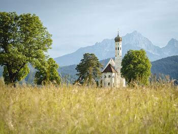 Church on field by building against sky