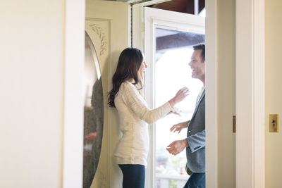 Happy woman looking at man while standing in doorway