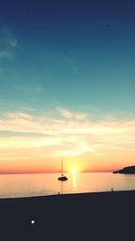 Silhouette sailboat in sea against sky during sunset