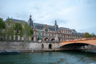 Arch bridge over river against buildings