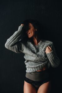 Smiling woman wearing sweater while posing against gray background