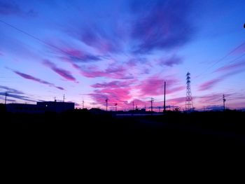 Silhouette electricity pylons against sky during sunset