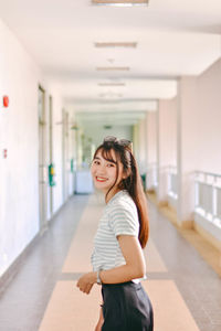 Portrait of young woman standing at corridor in building