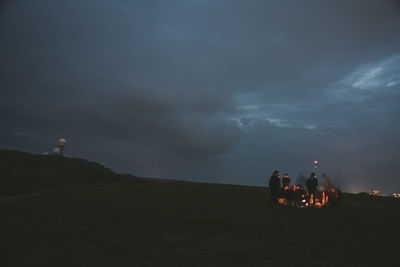 People on road by mountain against sky at dusk