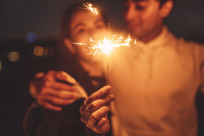 Midsection of man holding sparkler at night