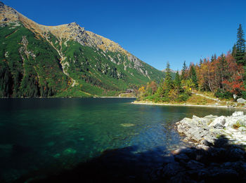 Scenic view of lake and mountains against clear blue sky