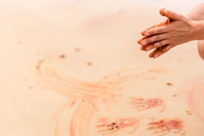 Cropped hands over sand at beach