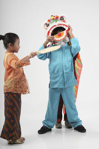 Side view of smiling girl with friends wearing costume against white background