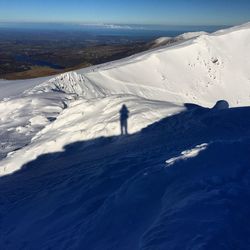 Shadow of person on snowcapped mountains during sunny day