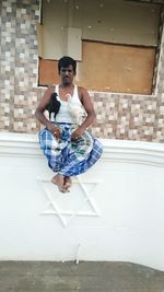 Portrait of woman sitting against wall