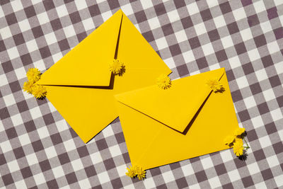 Beautiful little yellow chamomile daisies flowers on two postal yellow envelopes, empty paper note