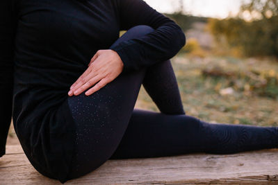 Midsection of woman sitting on wooden bench at while exercising