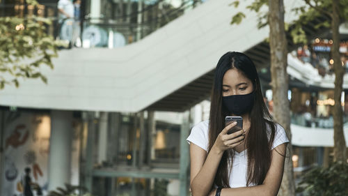 Woman photographing with mobile phone standing outdoors