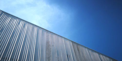 Low angle view of corrugated iron against blue sky