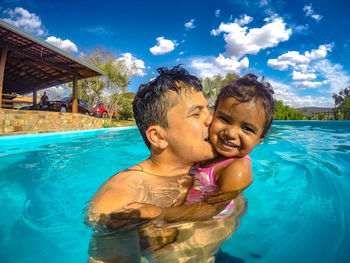 Portrait of father with daughter in swimming pool