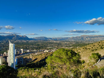 Aerial view of city buildings against blue sky