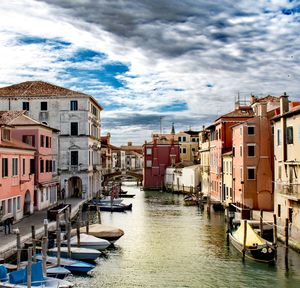 Boats moored in canal amidst buildings in city