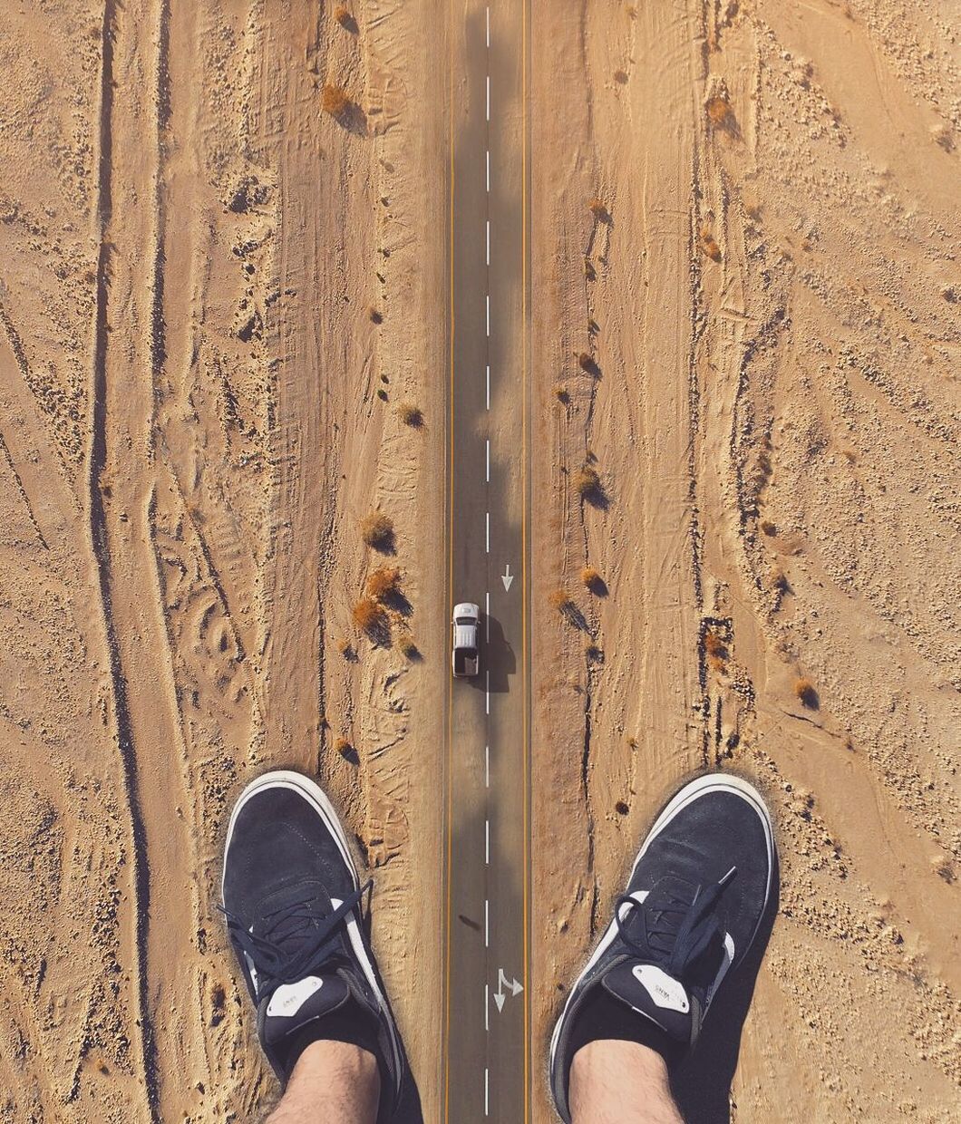 LOW SECTION OF PERSON STANDING ON SAND AT LAND