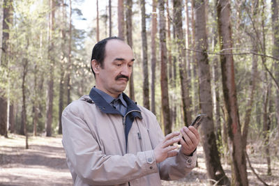 Young man using mobile phone in forest