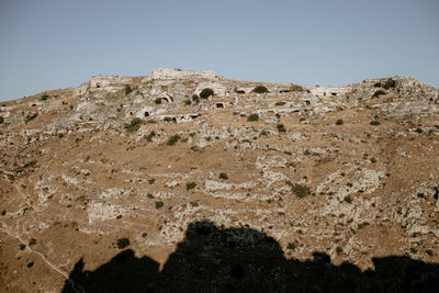 Low angle view of rocks on mountain against clear sky