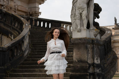 Portrait of smiling young woman standing against building