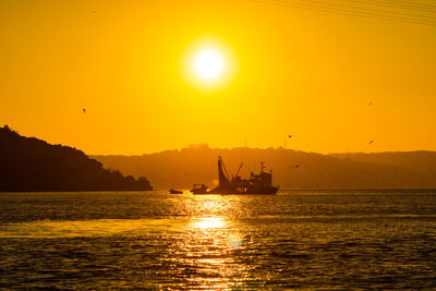 Silhouette boat in sea against sky during sunset