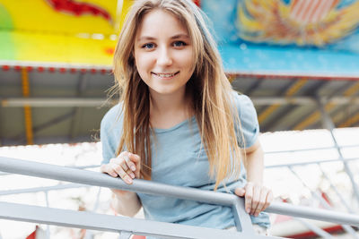 Portrait of young woman sitting on railing
