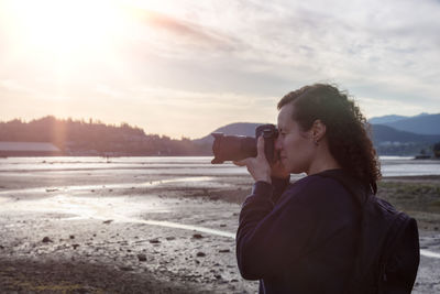 Side view of man photographing against sky