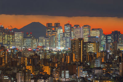 Illuminated cityscape against sky during sunset