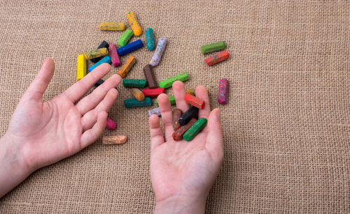 Cropped hands of child holding crayons on jute