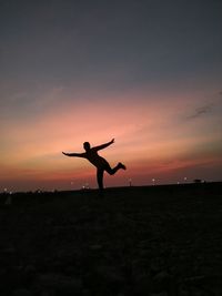 Silhouette man with arms outstretched against sky during sunset