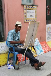 Full length of man sitting against wall