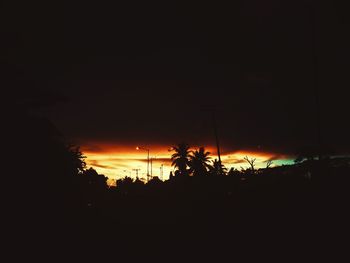 Silhouette trees on field against sky at sunset