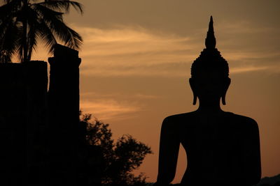 Silhouette statue against sky at sunset