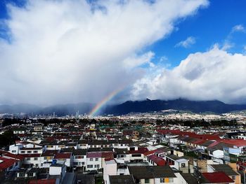 Aerial view of rainbow over buildings in city against sky