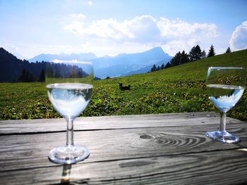 White drinking glass on table against sky