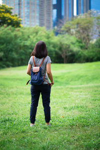 Rear view of woman with backpack standing on grassy field