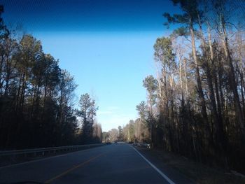 Road amidst trees against sky