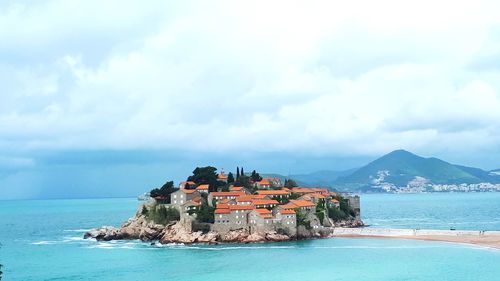 Scenic view of sea by buildings against sky