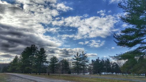 Road passing through landscape against cloudy sky