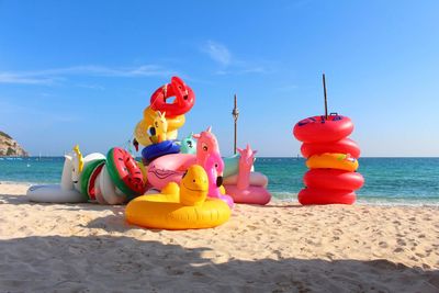 Multi colored toys on beach against sky