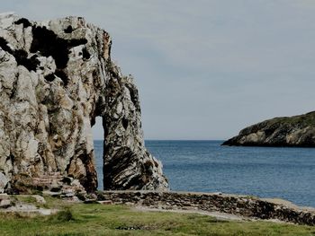 Rock formation on beach against sky