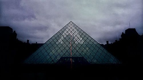 Low angle view of modern building against cloudy sky