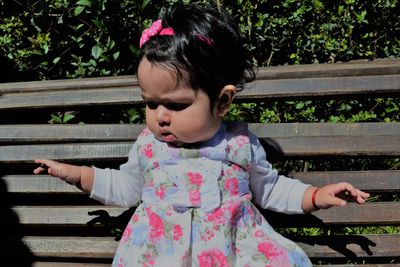 Cute baby girl sitting on park bench